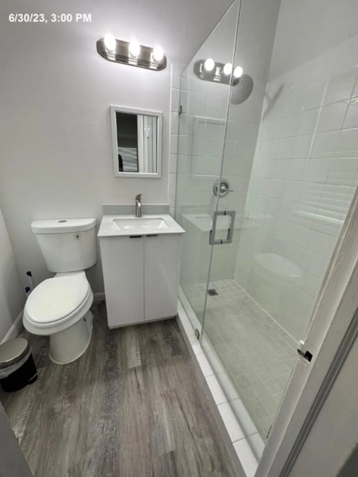 A modern bathroom featuring a sleek vanity with a sink, a glass shower enclosure, and a large mirror. The serene and refreshing ambiance makes it ideal for morning routines or a relaxing shower at day's end.